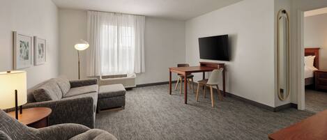 Una habitación de hotel con sofá, una mesita, televisor y espejo.
