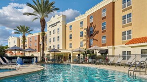 Un hotel con piscina, palmeras y mobiliario exterior.