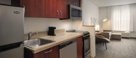 A compact kitchen with a refrigerator, microwave, stove, and dishwasher.