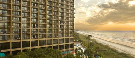 Un hotel de gran altura con múltiples balcones con vista a la playa.