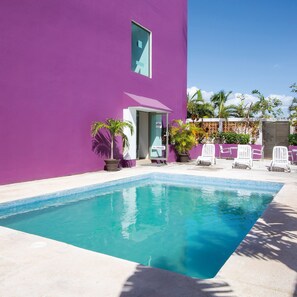 Una piscina al aire libre, sombrillas, sillones reclinables de piscina