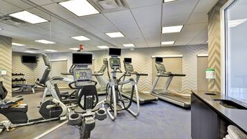 A gym with various exercise equipment, including treadmills, stationary bikes, and elliptical machines.