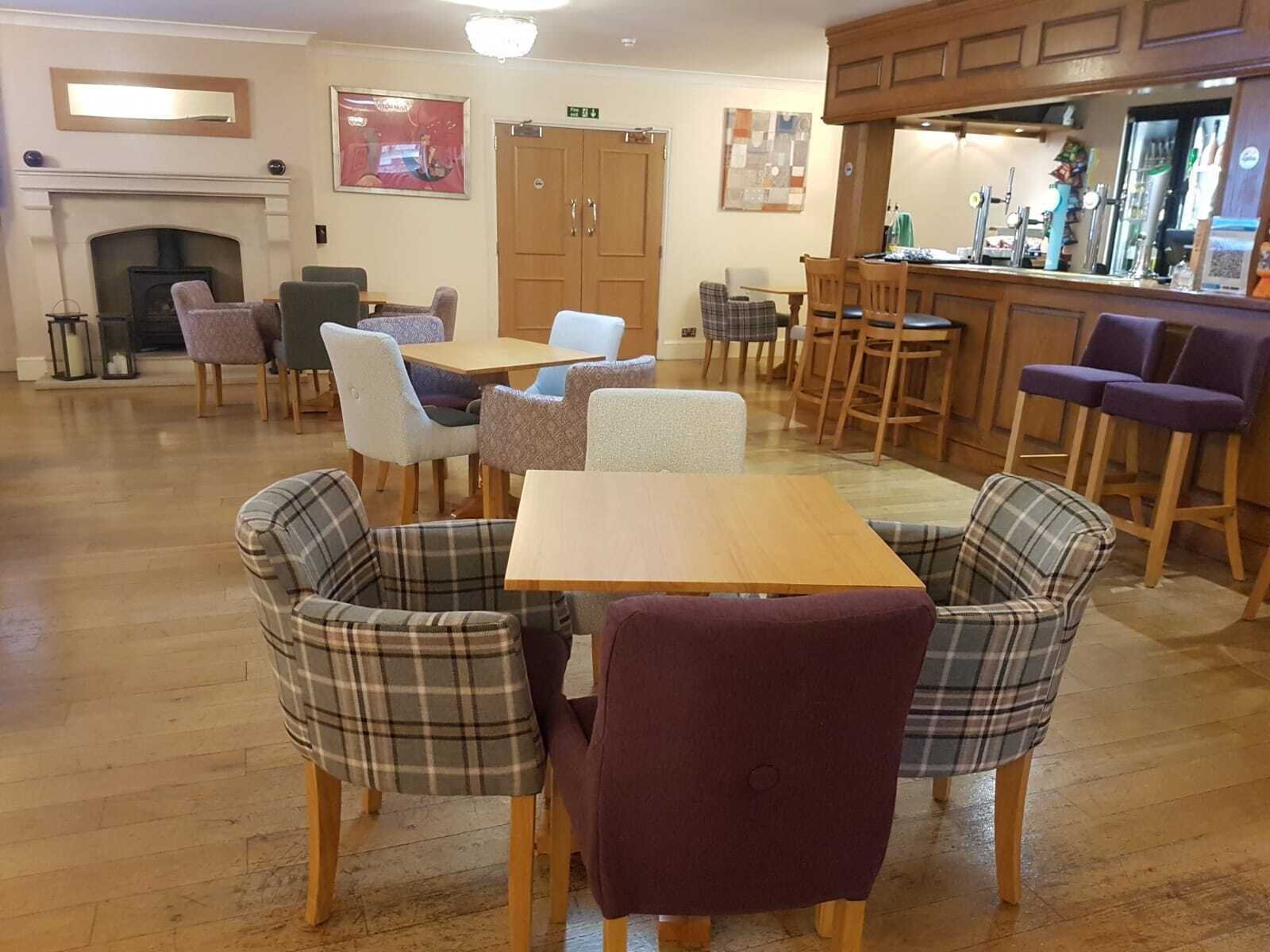 Un comedor acogedor con sillas de cuadros, una mesa de madera y una barra con taburetes.