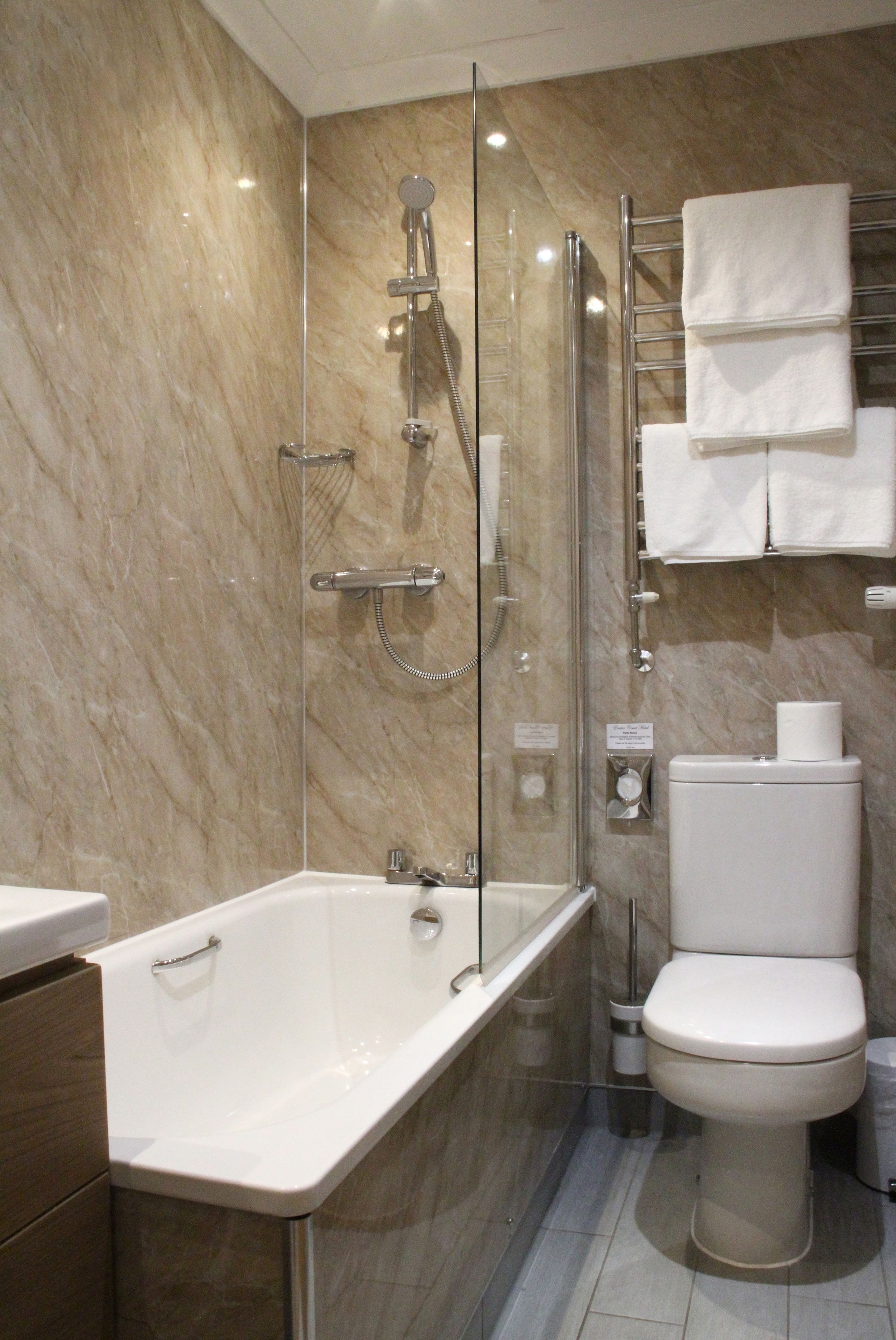 Un baño moderno con ducha de vidrio, una bañera blanca y un inodoro.