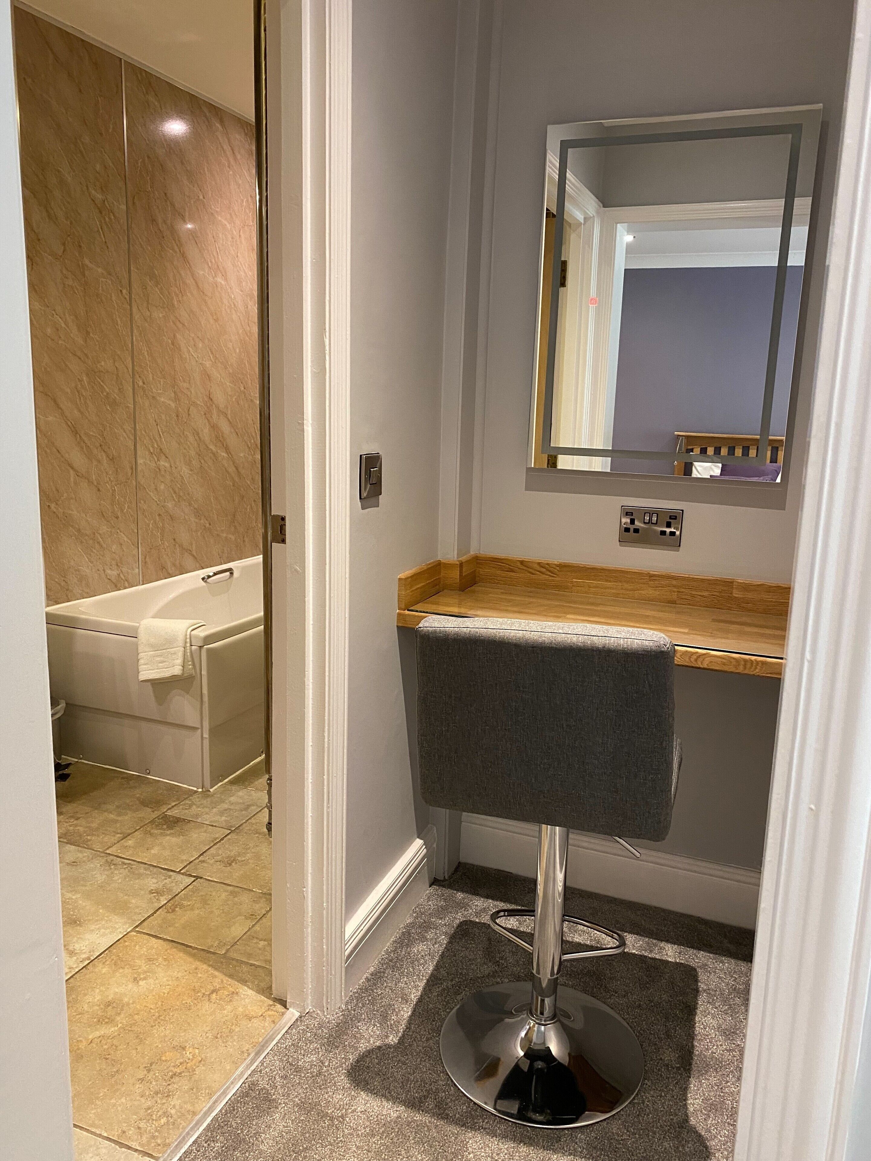 A bathroom with a bathtub, a vanity with a mirror, and a shower area.