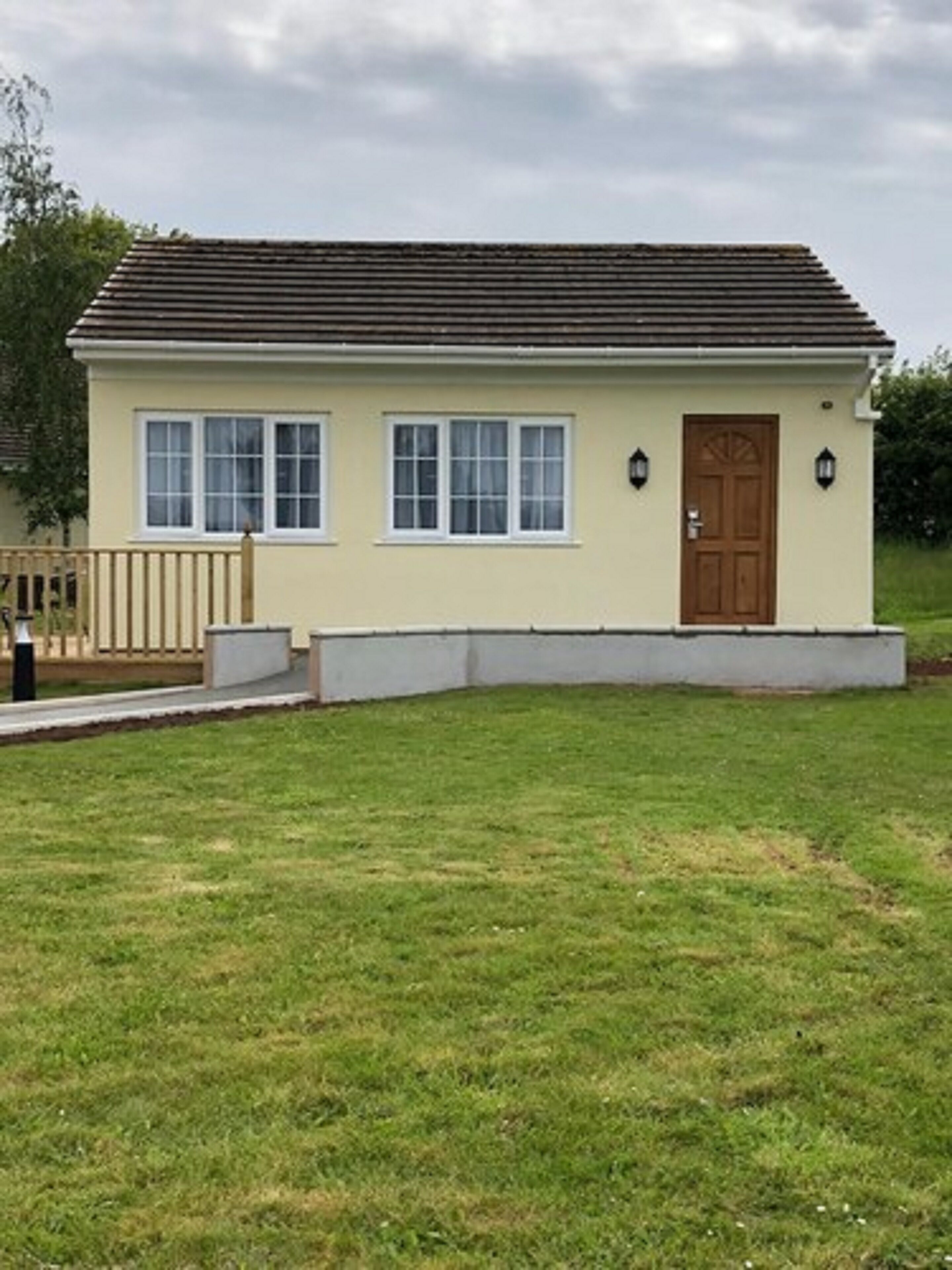 Une maison de plain-pied avec un toit plat, une porte d’entrée et deux fenêtres au rez-de-chaussée.