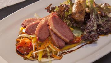A plate of food with sliced meat, vegetables, and a salad.