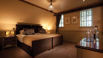 A bedroom with a large bed, bedside tables, a hanging light fixture, a window with blinds, and a bedside table with a lamp.