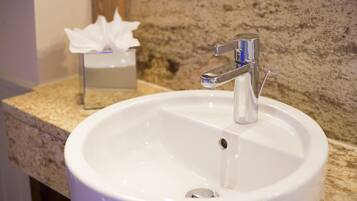 Un lavamanos blanco con grifo cromado en un baño con encimera de granito.