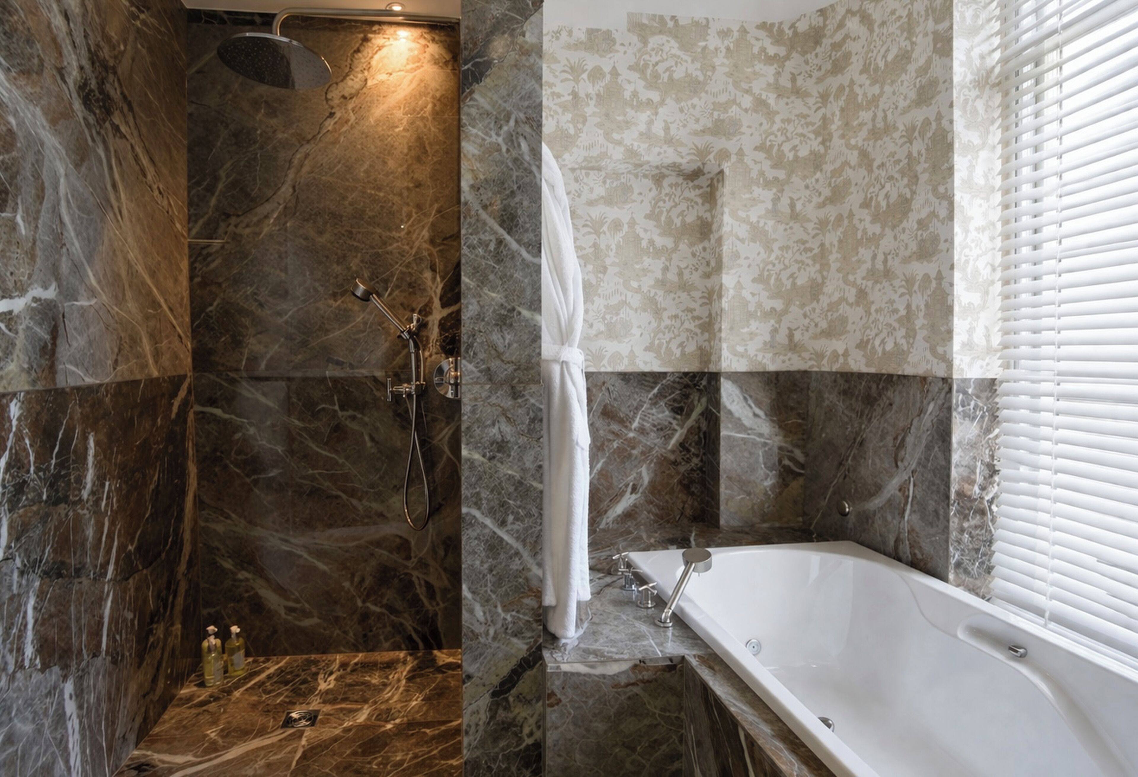 A bathroom with a shower, a bathtub, and marble walls.