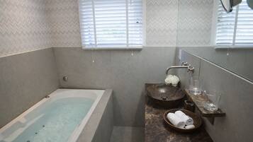 A modern bathroom with a bathtub, a wooden bowl sink, and a marble countertop.