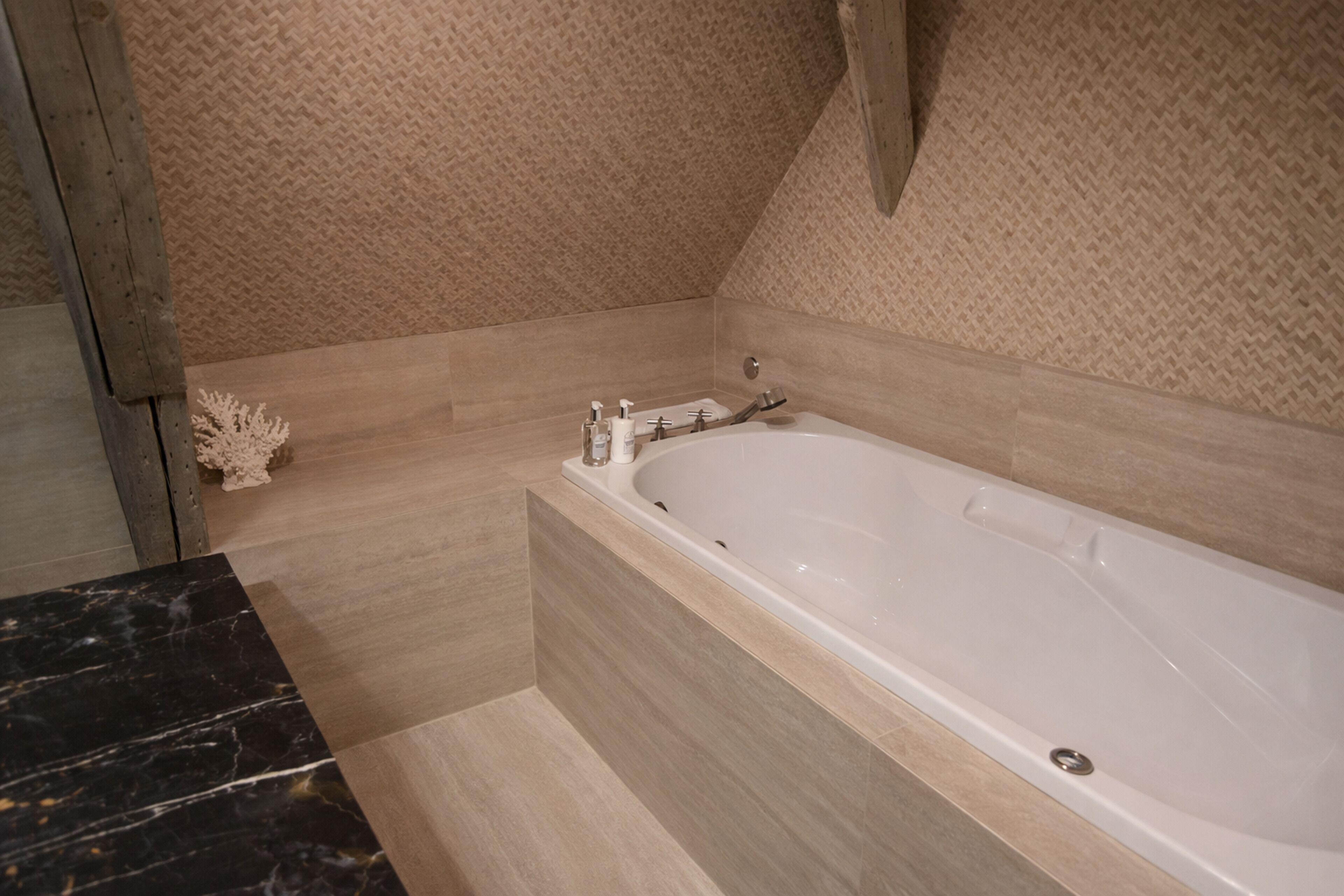 Ein modernes Badezimmer mit einer freistehenden Badewanne, einer Marmorplatte und strukturierten Wandfliesen.
