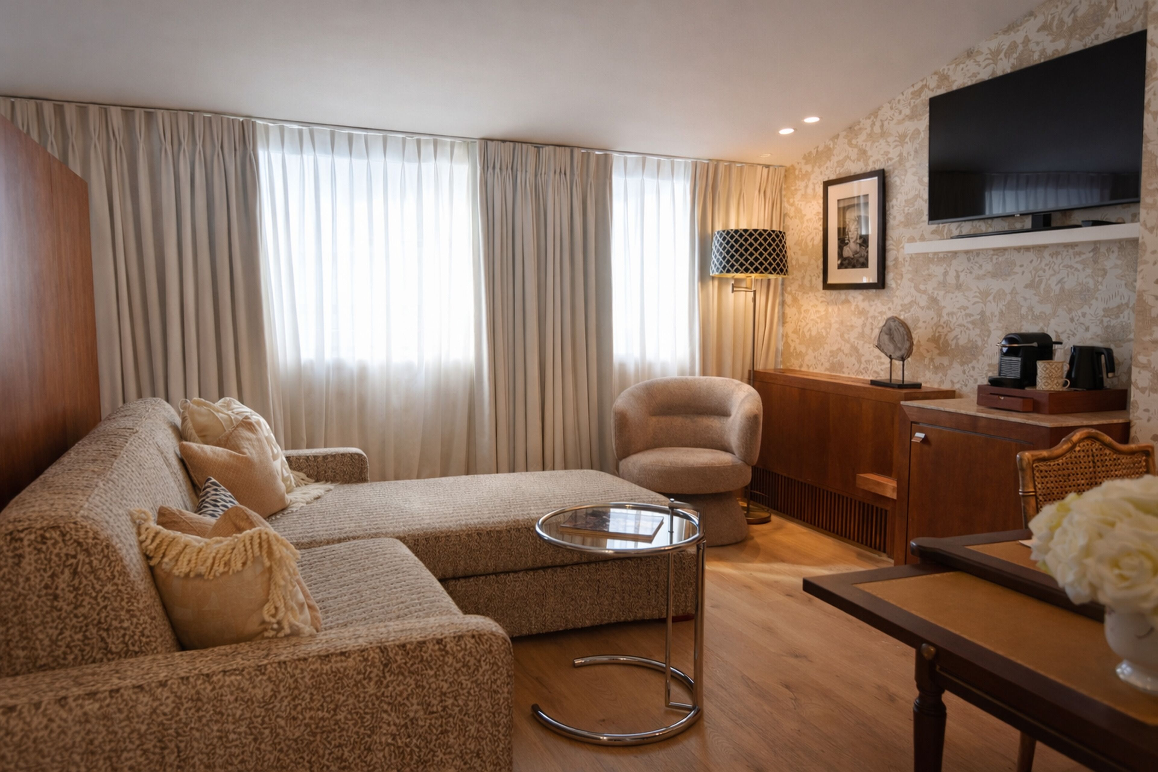 A living room with a sofa, armchair, coffee table, and a flat-screen TV mounted on the wall.