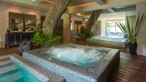 Un área de spa con un jacuzzi, un banco de piedra y un espejo grande.