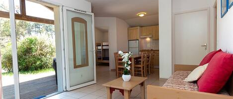 A compact living space with a sliding glass door leading to a balcony, a small dining area, and a kitchenette.