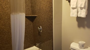 Une salle de bain équipée d'une baignoire, d'une douche, de toilettes et d'un porte-serviettes.