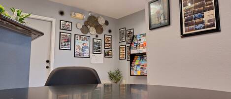 A conference room with a large table, framed photos, and a bookshelf filled with books.
