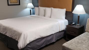 A hotel room with a large bed, two bedside tables with lamps, a chair, and a framed picture on the wall.