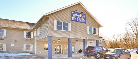 A two-story building with a sign for AmeriVii Inn & Suites. There are two cars parked in front.