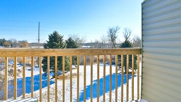 A wooden deck with a view of a snowy landscape and a clear blue sky.