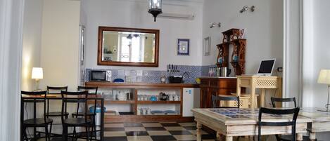 A kitchen with a checkered floor, wooden chairs, a dining table, and a hanging lantern.