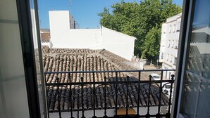 A balcony with a view of terracotta roof tiles and a white building in the background. - Hotel Polo (Ronda)