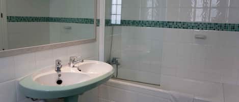 A bathroom with a sink, mirror, shower, and bathtub.