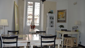 A dining area with a checkered floor, a white table with a patterned tablecloth, black chairs, and a white cabinet with glass doors. - Hotel Polo (Ronda)