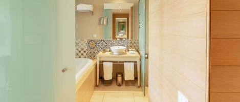 Une salle de bain moderne avec une baignoire, un lavabo doté d’un grand miroir et un mur recouvert de carreaux.