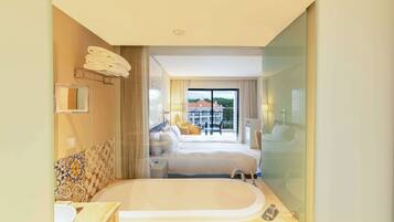 Une chambre d’hôtel dotée d’une grande baignoire, d’une chambre à coucher séparée avec balcon, et d’une salle de bain avec un lavabo et un miroir.