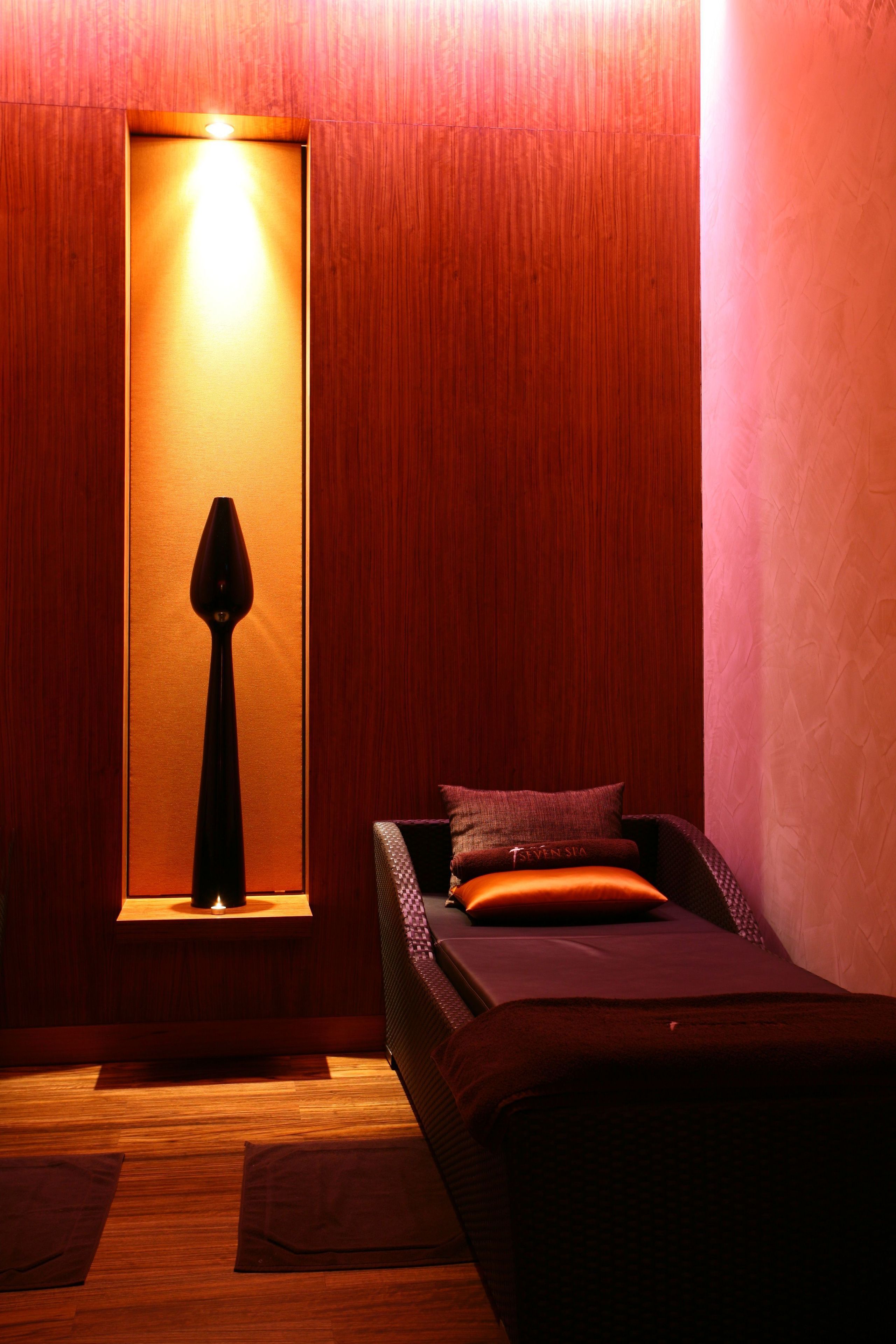 A room with a bed, a window with a lamp, and wooden walls.