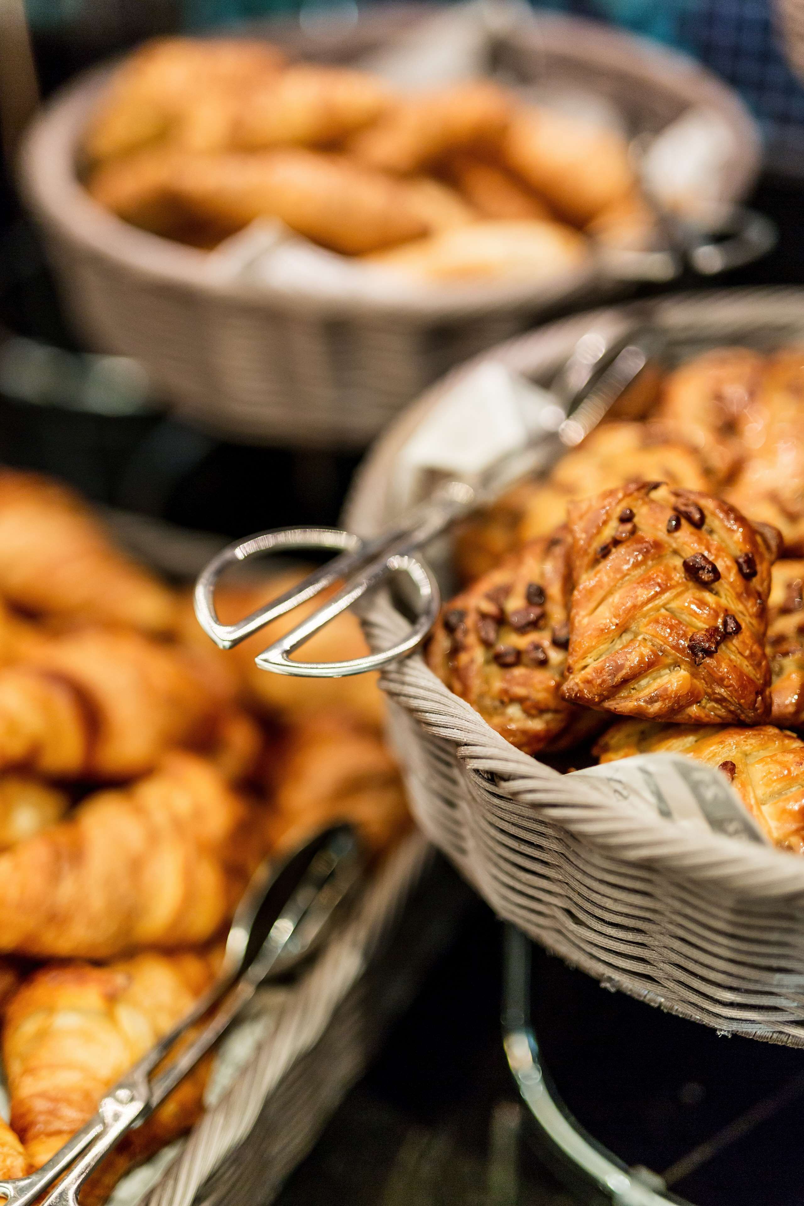 Une variété de produits de boulangerie présentés dans des paniers, notamment des croissants et des viennoiseries aux pépites de chocolat.