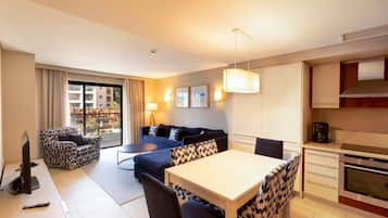 Ein modernes Hotelzimmer mit Sofa, Esstisch und Küchenzeile.