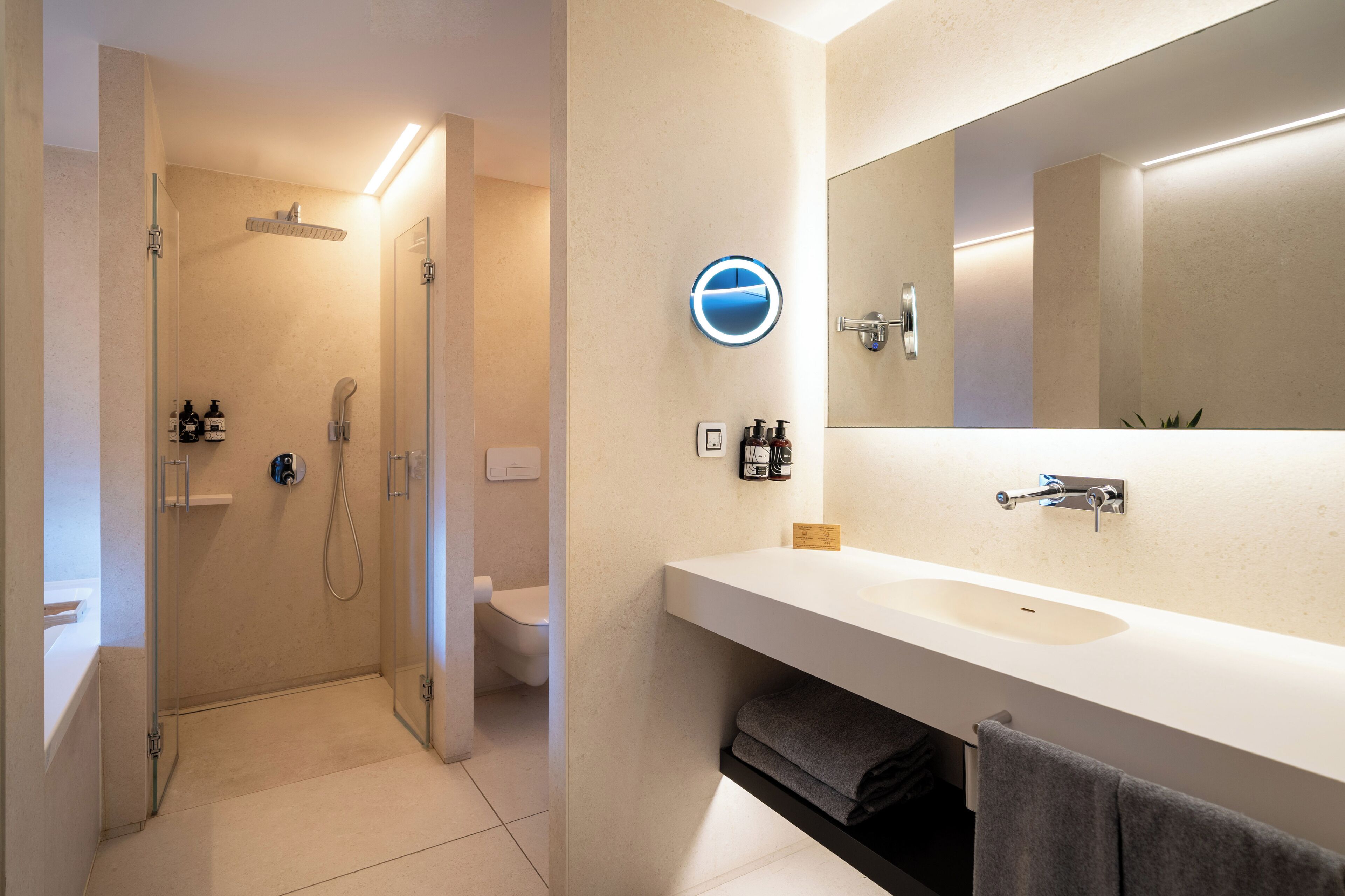 Une salle de bain moderne avec une douche à parois de verre, un lavabo blanc et un grand miroir.