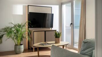 Una sala de estar moderna con televisor de pantalla plana, un sofá, una mesa de centro y dos plantas en macetas.