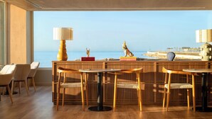 A dining area with wooden furniture, a view of the sea, and a decorative statue.