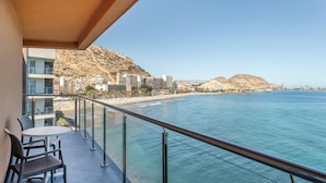 A balcony with a view of the sea and a cityscape.