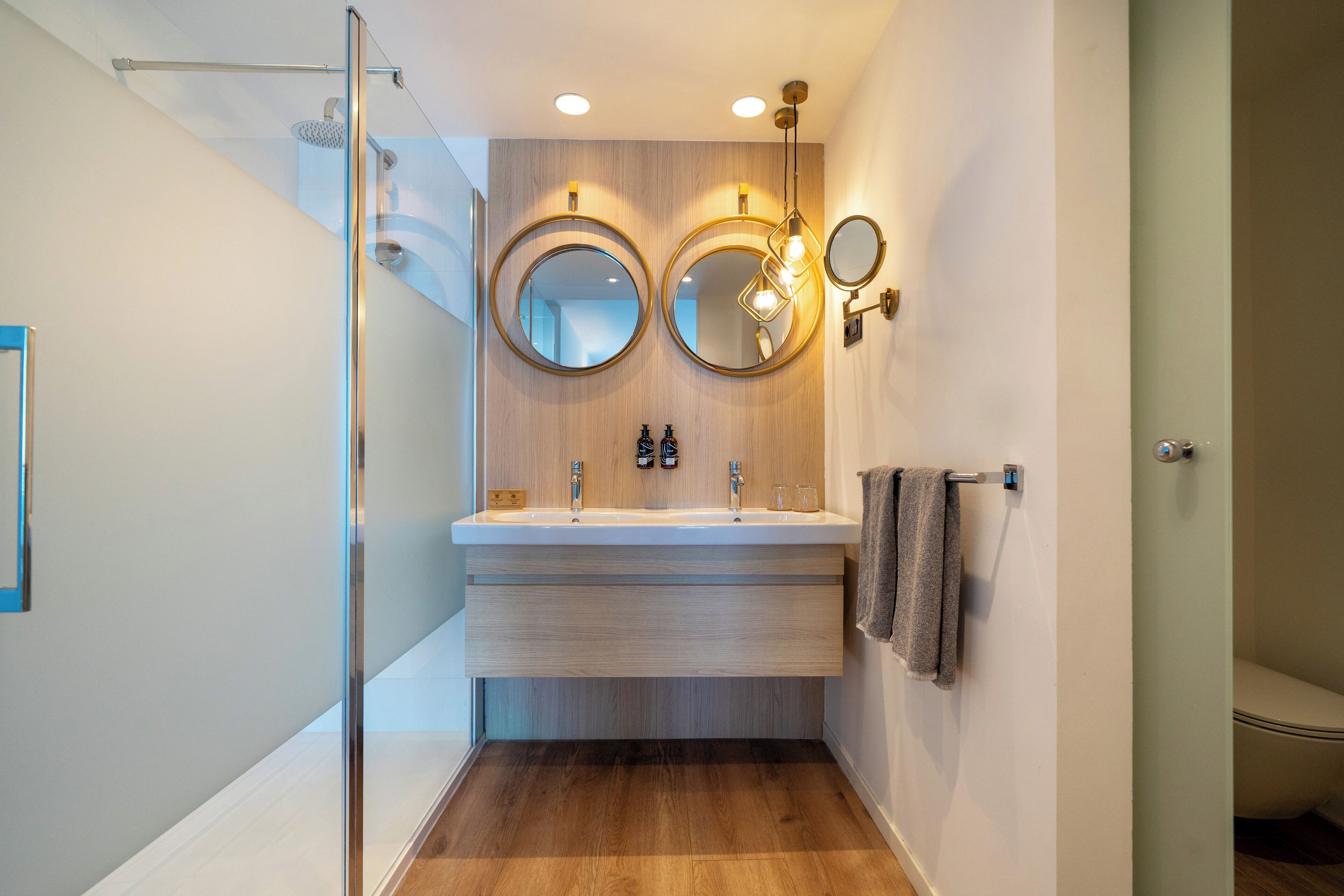 Un baño moderno con cabina de ducha de vidrio, un tocador doble y dos espejos montados en la pared.