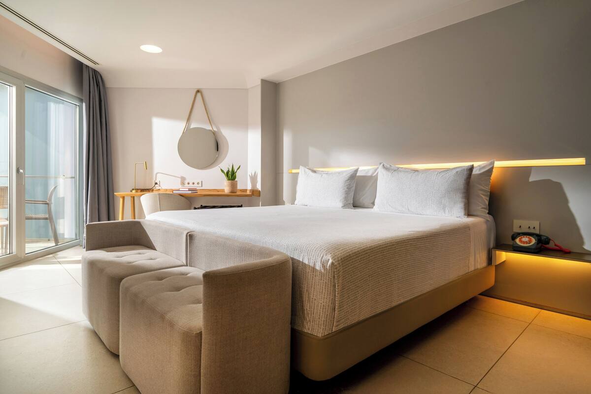 A modern bedroom with a large bed, a desk, and a seating area.