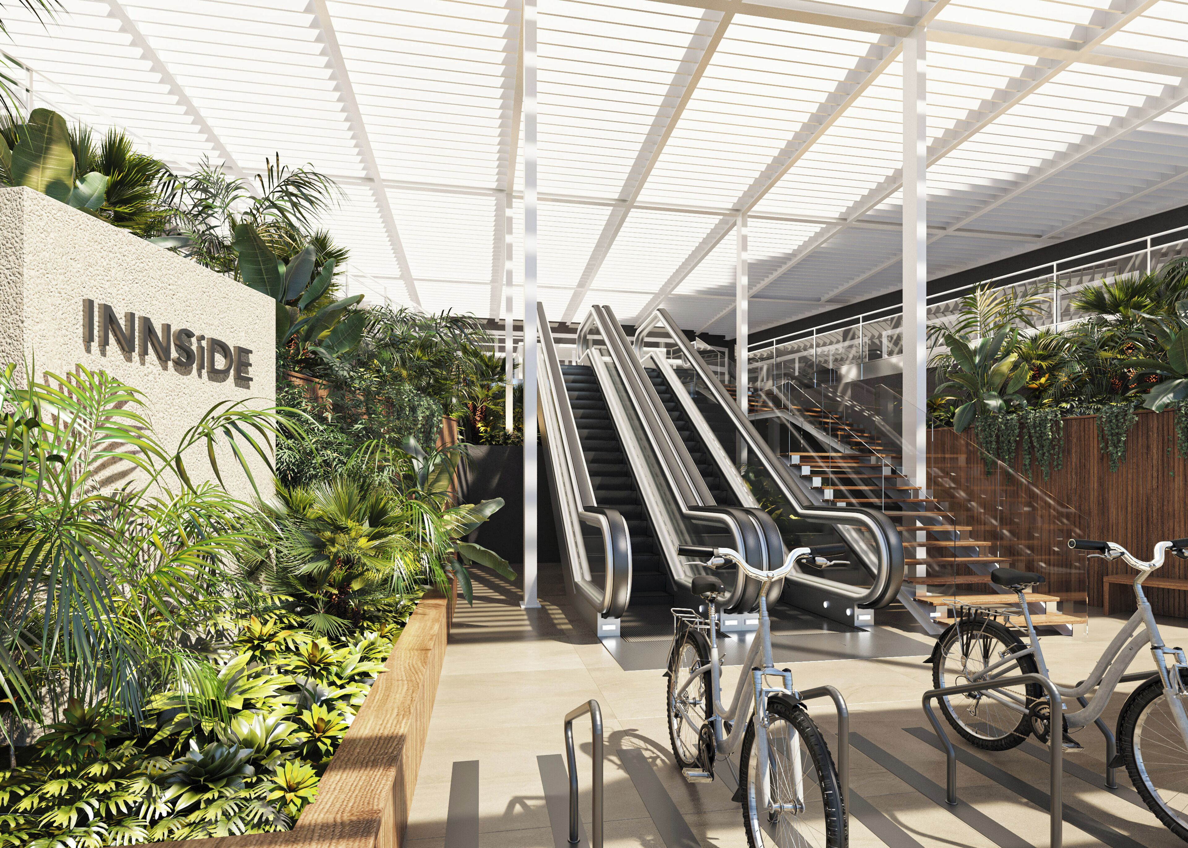 Un espacio interior con escaleras mecánicas, una bicicleta y un cartel que dice "INNSIDE".