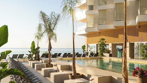 A poolside area with lounge chairs, planters, and a view of the ocean.