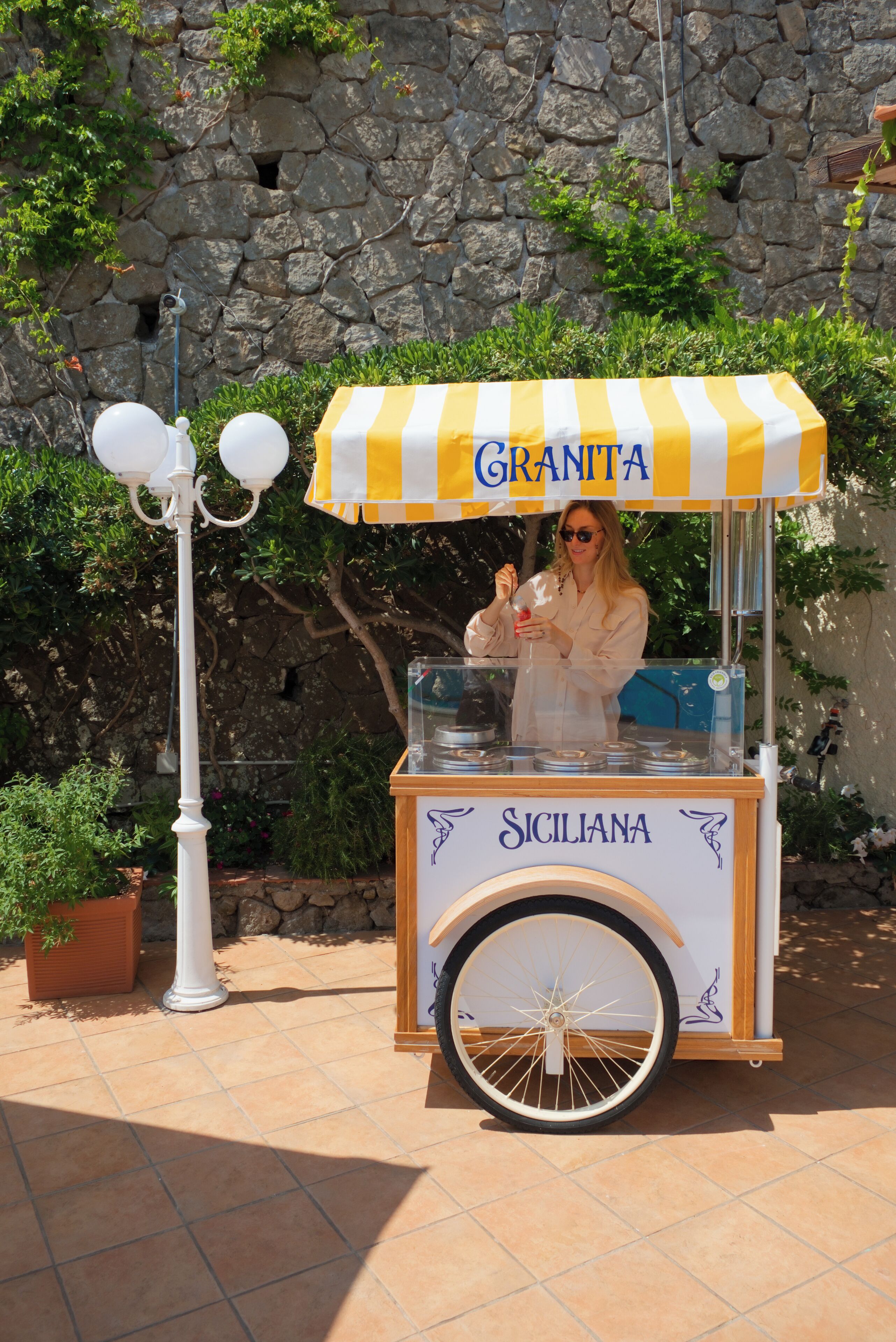A food cart with a yellow and white striped canopy labeled 'GRANTTA' and 'SICILIANA' on the side.
