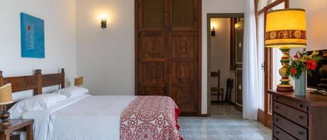 A bedroom with a bed, a dresser, a lamp, and a door.