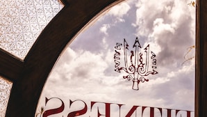 A view through a glass door with the word "ENTERTAINMENT" and a trident symbol. - Hotel Carasco (Lipari)