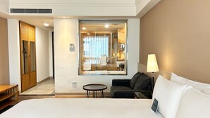A hotel room with a large bed, a small round table, a sofa, a lamp, and a mirror. - Azure Hotel (Hualien City)