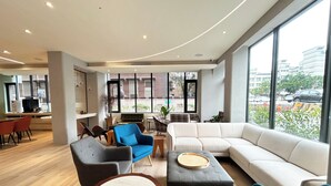 A modern living area with a large sofa, a coffee table, and a dining table with chairs. - Azure Hotel (Hualien City)