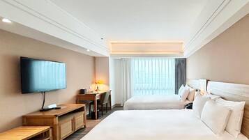 Une chambre d’hôtel avec un grand lit, un bureau avec une chaise, une télévision et une fenêtre avec des rideaux.
