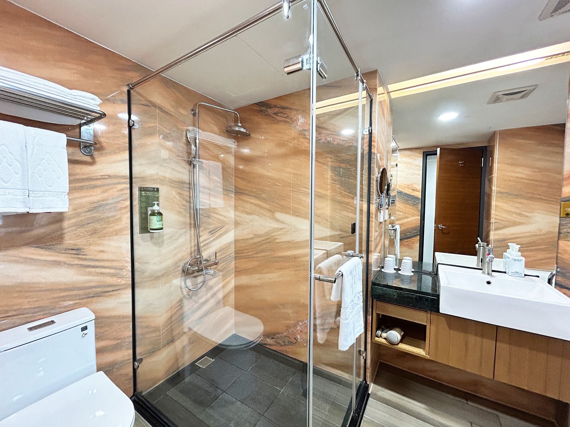 A modern bathroom with a glass-enclosed shower, a white sink, and a large mirror.