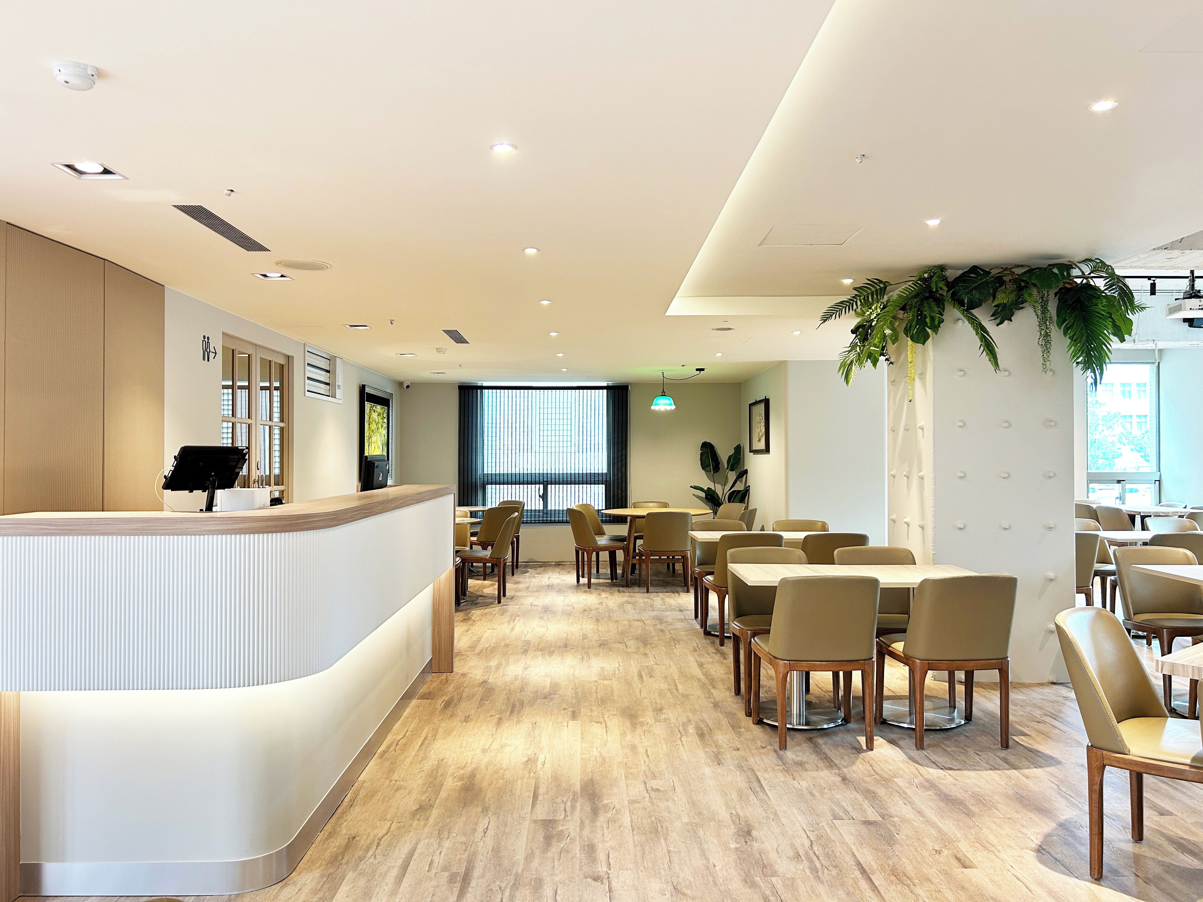 A modern hotel lobby with a reception desk, seating area, and large windows.