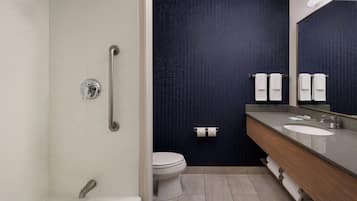 Un baño moderno con cabina de ducha, inodoro y tocador con un espejo grande.